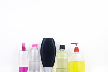 Isolated bottles of detergents on a white background. The hand takes the jars of detergents. In the photo, shampoo, micellar water, liquid soap and mouthwash. Household chemicals in colored containers