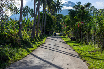 Tropical road landscape with distant mountain. Motorbike trip in South Asia. Volcanic island of the Philippines optimistic pandscape. Summer vacation travel banner template. Green palm trees road