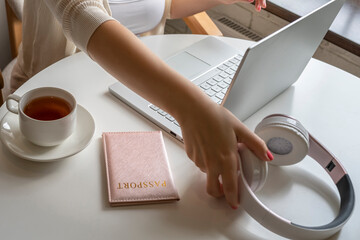 Woman tourist having breakfast with cup of coffee putting passport and headphones on the table sitting near window in cafe in airport. Travel concept