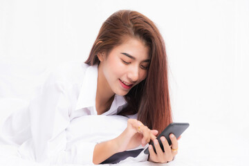 Fototapeta premium Young Asian woman using smart phone in bedroom at home happy and smile.