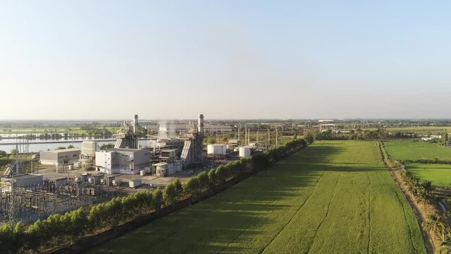 4K.Aerial view of Oil and Gas refinery industry plant.air pollution from smokestacks under cloudy sky with green Meadow.
