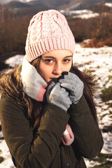 Young woman portrait on a winter landscape well wrapped up for cold