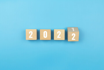 Happy new year. Wooden cube with the number 2021 to 2022 on blue background