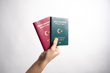 Woman holding two Turkish passport on the white background.A red turkish passport and a green...