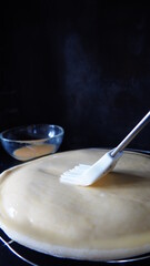 Brushing a raw puff pastry pie with egg wash, black background, vertical 16:9 picture, space for text