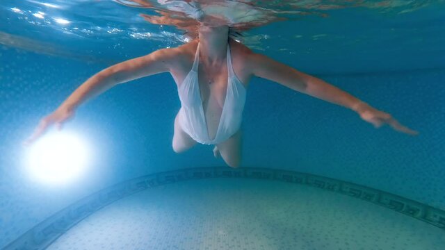 Underwater view of young pregnant woman expecting baby swimming and relaxing in swimming pool. Concept of pregnancy healthcare and sports.