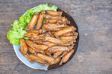 Fried chicken wings with fish sauce with salad vegetables on a white plate placed on a wooden table. Close-up photo. Space for text. Concept of foods