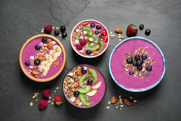 Obraz na płótnie Canvas Acai smoothie bowls with granola and fruits on black table, flat lay