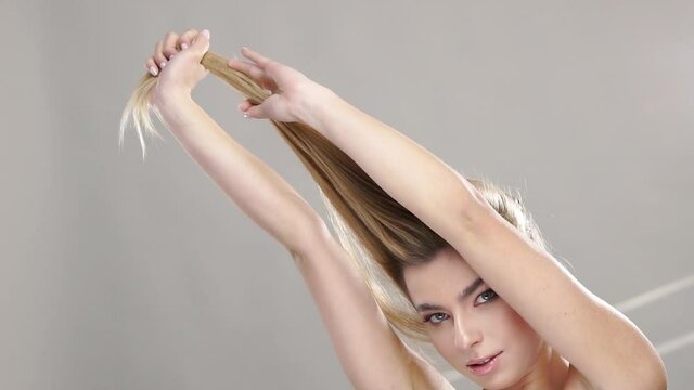 pretty girl pulls the hair up on grey background