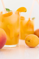 Ripe apricots and glass of apricot juice over white wood background