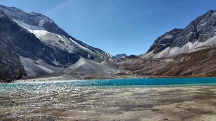 crystal clear blue and sparkling lake in the snowy mountain valley peak in the sunny day