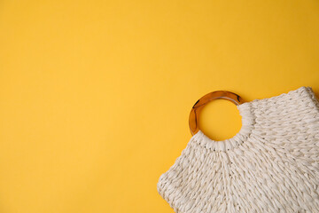 Stylish straw bag on yellow background, top view with space for text. Summer accessory