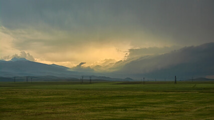 Stormy sunset over the field with electric poles