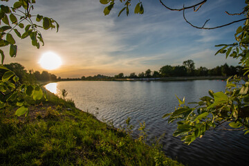 beautiful werdersee, a river in bremen surrounded by green at sunset - obrazy, fototapety, plakaty