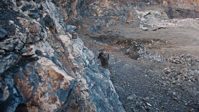 The soldier of special forces moves along a gorge in the mountains with machine gun during military operation. Slow motion