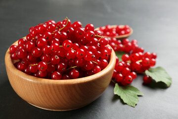 Ripe red currants in wooden bowl on black table