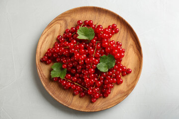 Delicious red currants and leaves on light table, top view