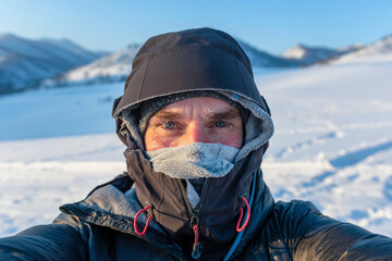 Fototapeta na wymiar Extremely cold weather. Portrait of middle age European man with face covered with snow frost.