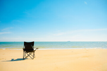 Black chair on the beach with sea in background