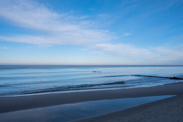 calm blue baltic sea against a blue sky with white cirrus clouds and an empty sandy beach, the city of Pionersky, Kaliningrad region