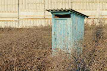 Toilet cubicle. Rustic toilet in the middle of dry grass.