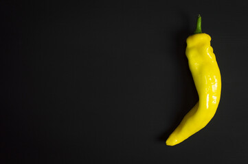 yellow long pepper isolated on the right on black background
