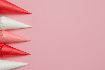 Multicolored glazing in icing bags on a pink background.  Set for decorating desserts.  Icing for gingerbread, brownies and cakes in pastry bags. Cake decorating tools.