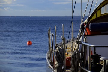 Barca a vela attraccata, mare calmo cielo azzurro, corde e boe visibili