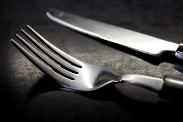 Close-up, a fork and a kitchen knife resting on the anthracite counter