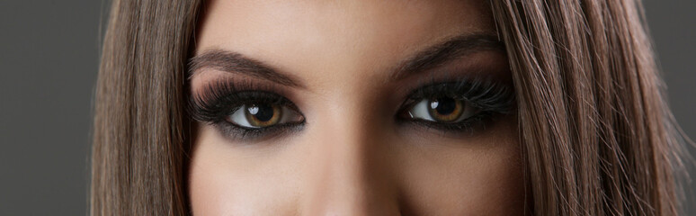 Obraz premium Close up of woman eyes with smokey eyes makeup and fake lashes, studio shot, looking to camera.