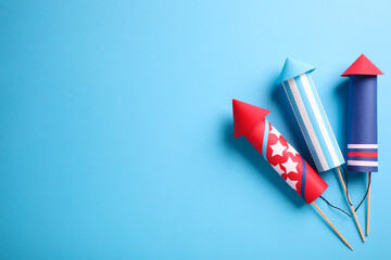 Firework rockets on light blue background, flat lay. Space for text