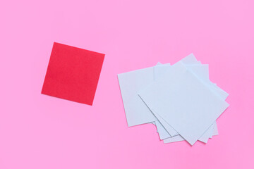 note papers with a red and group of blue on pink background , uniqueness concept