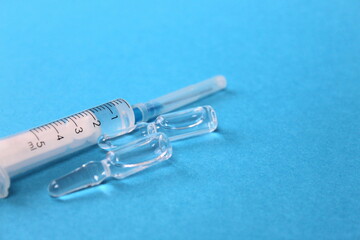 Syringe and ampoules with medicine lie on a blue background