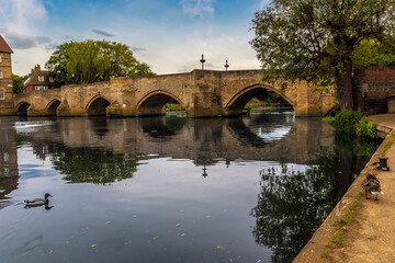 Fototapeta na wymiar The old bridge at Riverside, Godmanchester reflected in the River Great Ouse in springtime