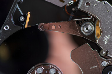 Component parts of a disassembled hard drive, close-up on a dark background.
