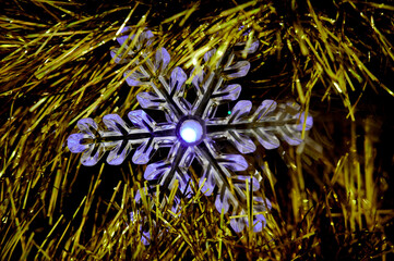 Christmas garland in the form of a snowflake on a golden Christmas tree
