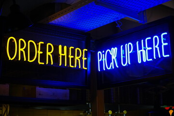 Order here and pick up here neon signs in a bar. 