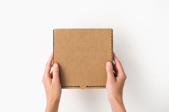 female hands holding a small cardboard box on a white background. packaging and delivery concept, top view