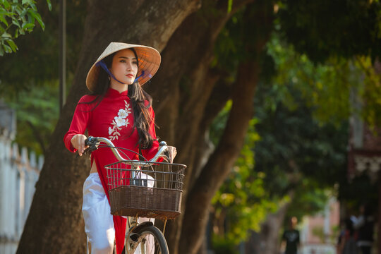 Portrait of Vietnamese girl traditional red dress,Beautiful young asian woman wearing Vietnam with bicycle