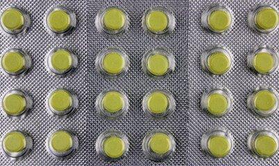 Background of small yellow pills in a blister pack