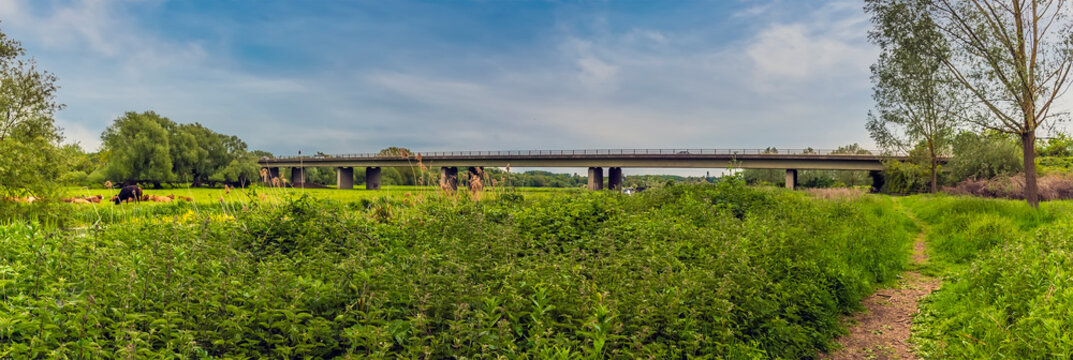 A panorama view from the banks of the River Nene towards the modern motorway viaduct for the A14 at Thrapston, UK in springtime