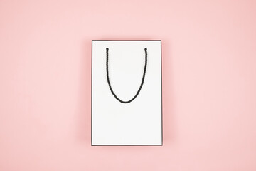 White shopping bag on pink background. A paper bag for shopping with red hearts. Valentines Day, Happy Womens day, Mothers Day sale.