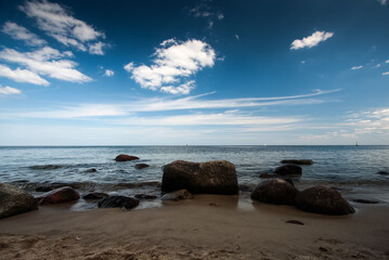 Clouds on blue sky over the stones, Baltic Sea, Gdynia, Poland