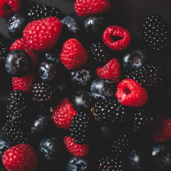 Detail of healthy sweet fresh blackberries, blueberries and raspberries on black background. Square format. Wallpaper fruit.