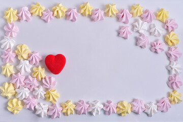 frame made of colored marshmallow on a white background and red heart