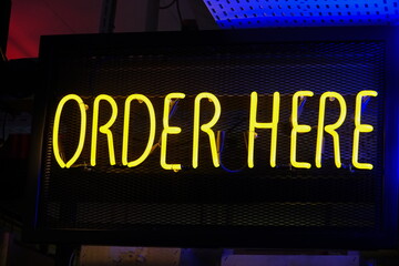 Order here neon sign in a bar. 