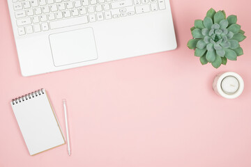 Flat lay home office desk. Women workspace with laptop, notebook, pen on pink background. Top view feminine background