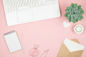 Femine office desktop with office accessories on pink background. Womens workspace with succulent, candle and cosmetics