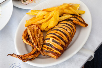 Grilled squid served with fries. Traditional Greek dish.