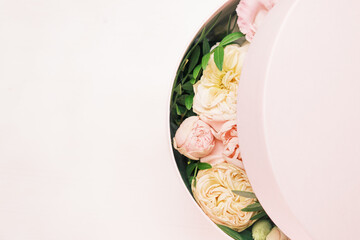 A stylish and delicate flower arrangement in a hat round box on the pink background with copy space. Gift box for 8 March, International Women Day, Mothers Day, St. Valentines Day